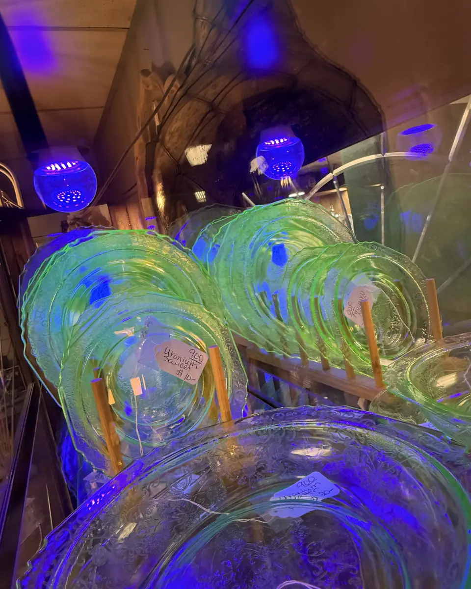 Green glass plates and serving pieces glowing under ultraviolet lights at Vintage 72