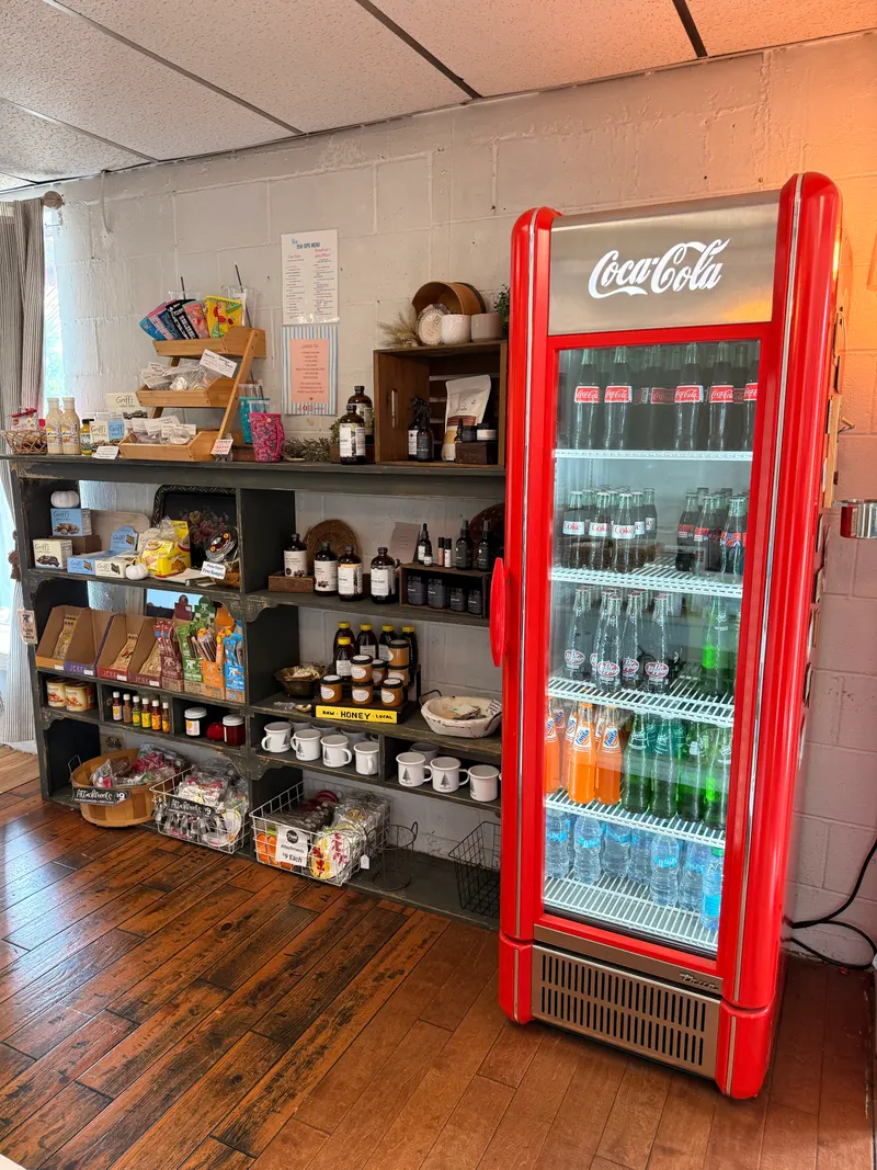 Snack shelves and local honey beside the red drinks cooler at Vintage 72